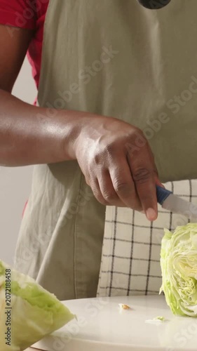 Vertical video: Placing cabbage on board, man in apron slicing with knife at home preparing meal