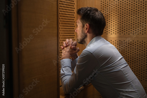 Fotografía Man penitent, in a confession booth, confessing sins to a priest to receive absolution and spiritual healing