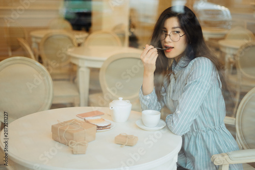 Obraz na płótnie beautiful asian girl enjoying an hot tea in cafe while waiting for someone and h