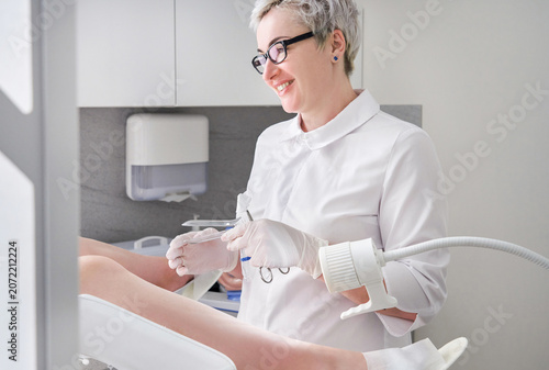 Foto Gynecologist with vaginal speculum in clinic before patient examination