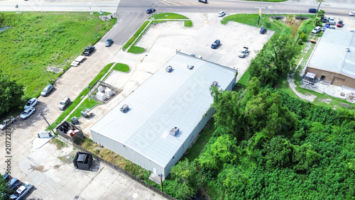 Aerial view of a commercial warehouse building with a parking lot and surrounding greenery
