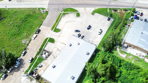 Aerial view of a commercial building with a parking lot and surrounding greenery
