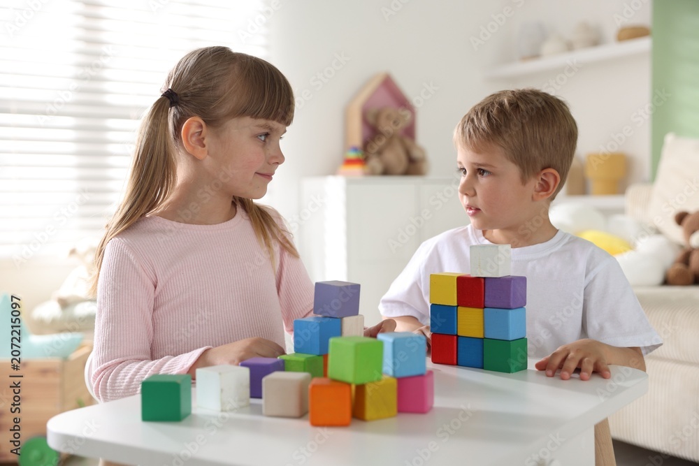 Fototapeta premium Little kids playing with colorful blocks at white table indoors