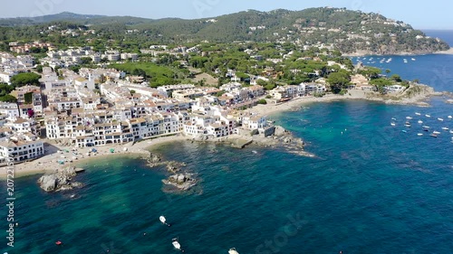 Aerial view of Calella de Palafrugell, a charming Costa Brava fishing village overlooking Canadell Beach, with whitewashed houses, turquoise waters and traditional Mediterranean character. 
