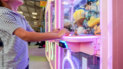 Fotografie Child's hands reaching for prizes inside a brightly lit arcade claw machine