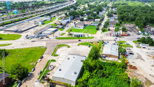 Aerial view of a commercial area with a large warehouse, parking lot, and nearby highway overpass