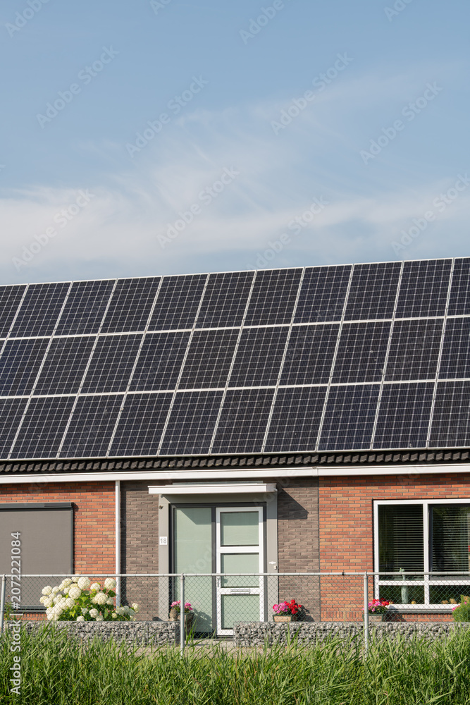 Fototapeta premium Breskens, Netherlands. Residential house with solar panels and garden illustrating sustainable living and decentralized energy production