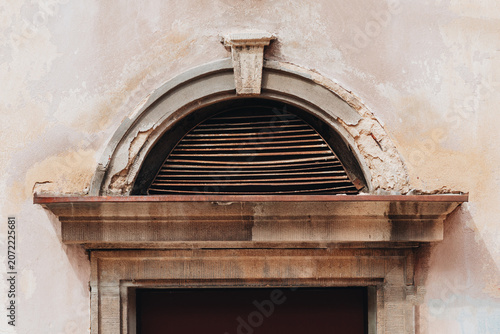 Weathered arched ventilation grille on an old historic building facade