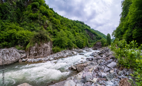 Scenic mountain river winding through a valley surrounded by green forest. Natural wilderness landscape showcasing rugged terrain and untouched beauty. Ideal for travel and outdoor adventure themes.