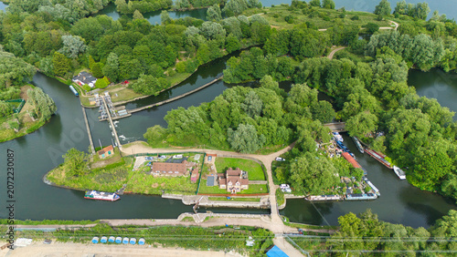 Aerial view of Feildes Weir Lock No.5 on the River Lee, featuring narrowboats, lush greenery, and historic lock structures in Hoddesdon, England, United Kingdom.
