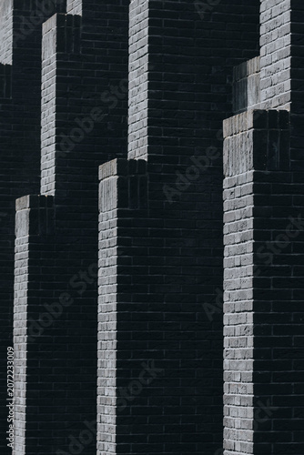 Dark brick facade with repeating columns and dramatic shadows