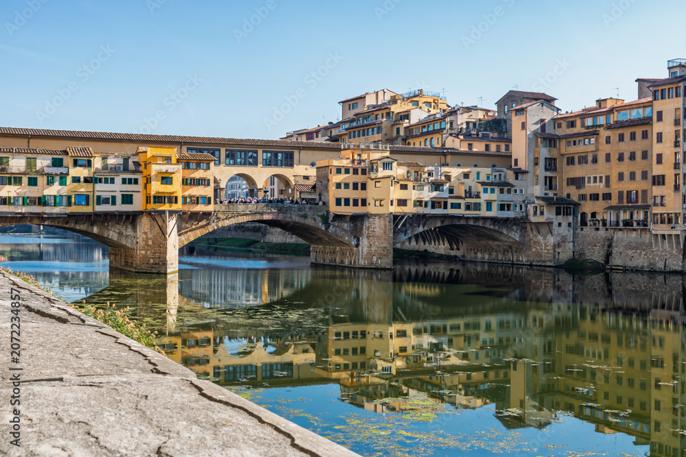 Fototapeta premium Famous historic Ponte Vecchio bridge and old buildings along the Arno river in Florence Italy