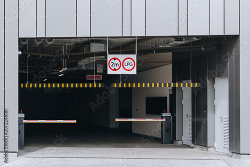 Modern underground parking garage entrance with barrier gates and height restriction sign