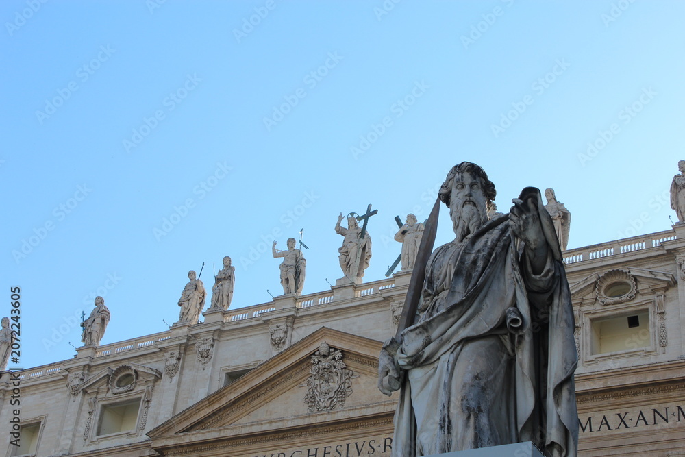 Obraz premium VATICAN CITY - JUNE 6, 2016: Statue of Saint Paul in front of St. Peter's Basilica facade under blue sky