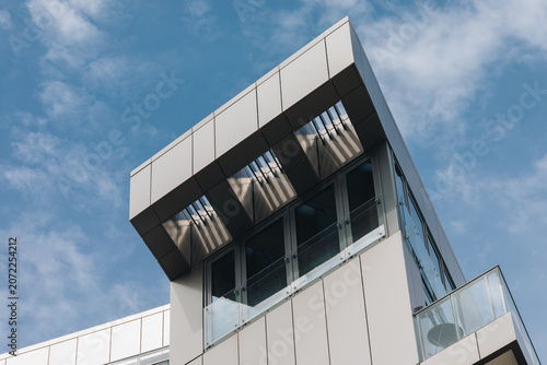 Modern white building facade with glass balconies against blue sky