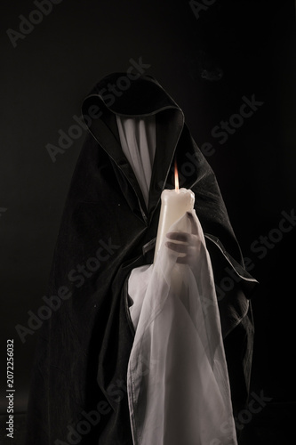 Fotografie Dark apparition of a woman draped in tulle, holding a large candle
