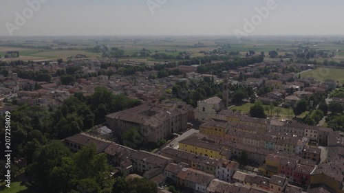 Aerial drone view of Soragna, Italy, featuring the historic fortress and adjacent church, surrounded by charming town architecture and green landscape in soft daylight.