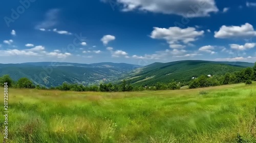 Panoramic view of rolling hills with vibrant green fields and blue sky
