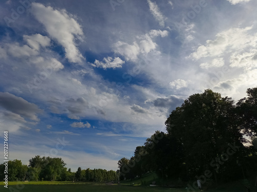 Green field and blue sky with beautiful fluffy clouds in sun summer day. Natural nature panorama cloudscape bright background