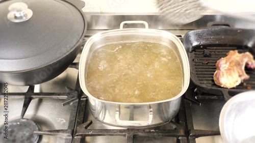 A Person Using a Slotted Spoon to Remove Boiled Meat and Bones from a Steaming Pot of Broth