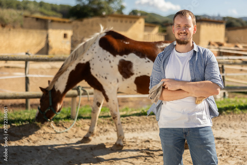 Photography Young man posing in paddock with tethered horse