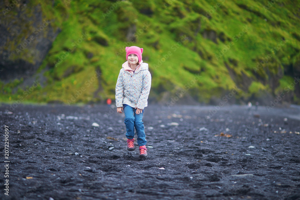 Fototapeta premium preschooler girl having fun on Reynisfjara Black Sand beach near Vik in Iceland