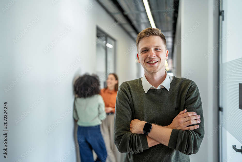 Fototapeta premium Smiling young man working in modern office hallway