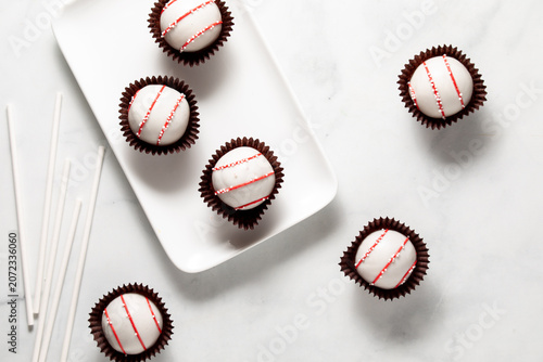 Decorated cake pops on and around a white rectangular platter.