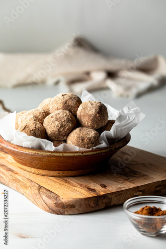 Homemade cinnamon coated energy balls in a dish with light coming from the left.