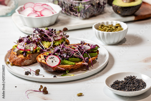 Avocado toast topped with fresh ingredients including purple radish microgreens.