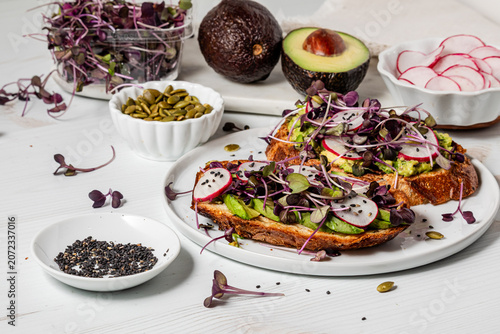 A plate of avocado toast servings with fresh ingredients all around.