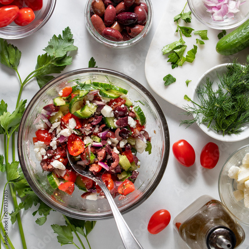A freshly made mediterranean salad with ingredients all around.