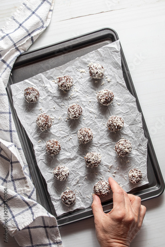 Chocolate coconut covered date energy balls on a baking sheet.