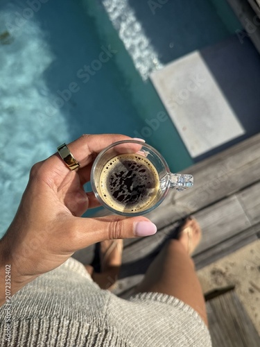 Obraz na płótnie Hand holding an espresso above a swimming pool, capturing a peaceful morning ritual in a luxury holiday setting with natural light and summer vibes