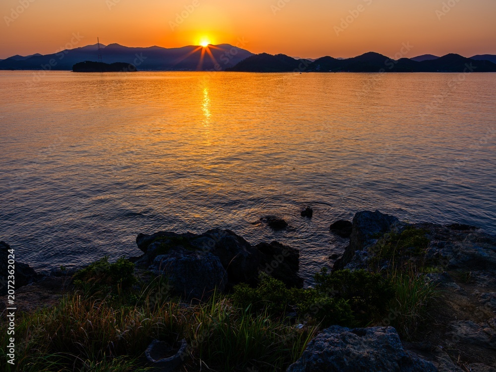 Φωτογραφία Dramatic sunrise over the mountains and sea with golden sun reflection on water