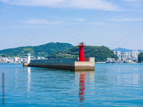 Fotografía Red and white lighthouses on the concrete breakwater with water reflection
(물 위의