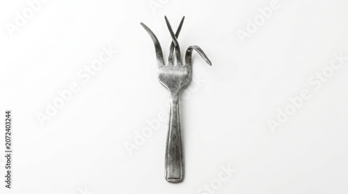 Close-up of modern stainless steel fork with intentionally bent tines on white background