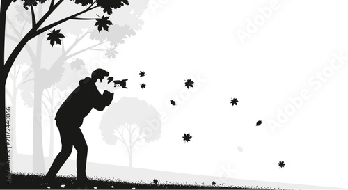 Silhouette of a photographer capturing falling autumn leaves in a park.