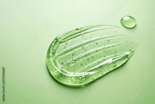Clear gel drop with bubbles on green surface showing texture and fluid shape