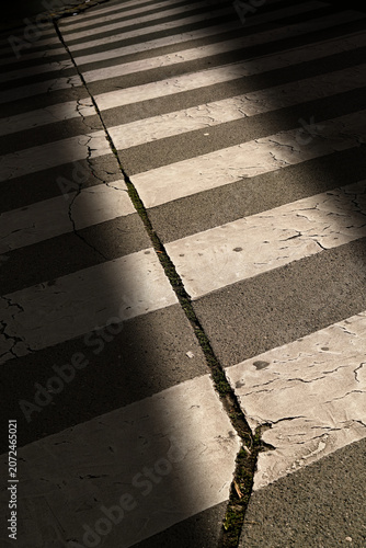 A Crosswalk, Zebra  crossing backlit by the setting sun, with shadows cast by parked cars