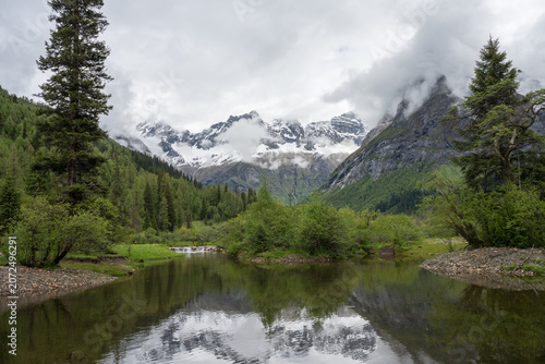 Natural Scenery of Valleys, Lakes, and Forests Beneath Snow-Capped Mountains Shrouded in Clouds and Mist