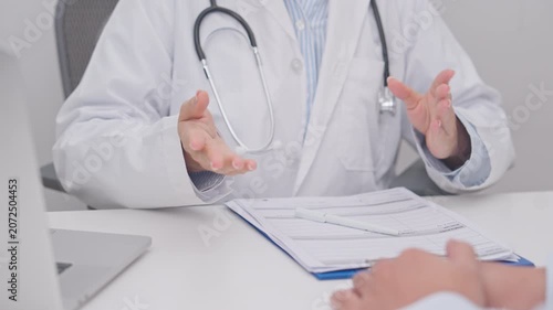Doctor and patient having a medical consultation in a hospital room, explaining a treatment plan, discussing diagnosis, and giving advice during a medical health checkup appointment in a clinic
