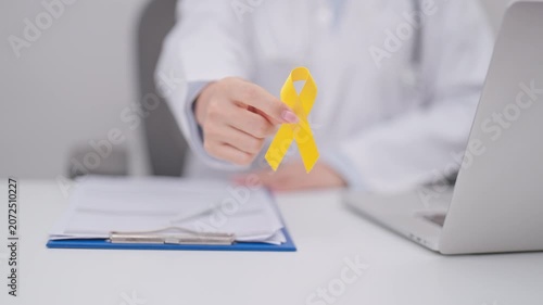 Doctor with Yellow Ribbon for concept of yellow September, Suicide prevention day, Childhood, July Sarcoma, bone and bladder cancer Awareness month, support survivor. Healthcare and World Cancer day