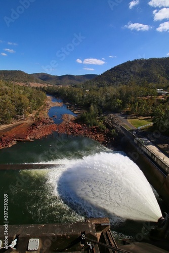 High-angle view of a powerful water discharge from Somerset Dam's spillway into the Stanley River valley, Queensland, Australia.
