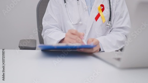 World hepatitis day awareness month, 28 July. doctor using laptop and report notes on notebook. Red and Yellow ribbon for Liver cancer, Jaundice, Cirrhosis, Failure, Enlarged, Hepatic Encephalopathy