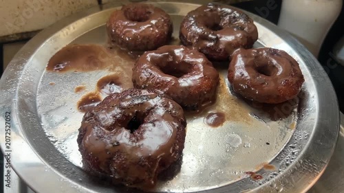 Homemade chocolate donuts prepared in India; professional food photography of traditional frosted ring doughnuts, sweet chocolate glaze coating, artisan home baking, and popular dessert confectionery.