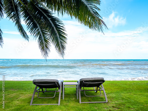 Photography Tropical beach resort with oceanfront lounge chairs under palm trees, featuring relaxing seaside vacation, coastal travel destination, luxury getaway, summer tourism, and tranquil nature scenery