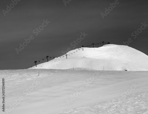 Black and white view on snowy ski slope and ropeway