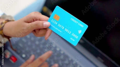 A hand holding a credit card in front of a computer. Illustration for online shopping, online transactions, etc.