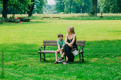 Mother with little son on park bench, green shade, summer, travel Europe